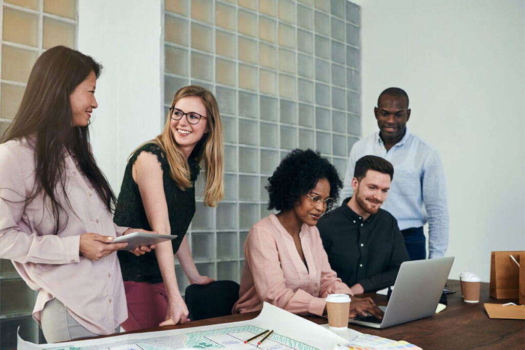 trois femmes et deux hommes collaborant autour d'une table de bureau, transformation digitale