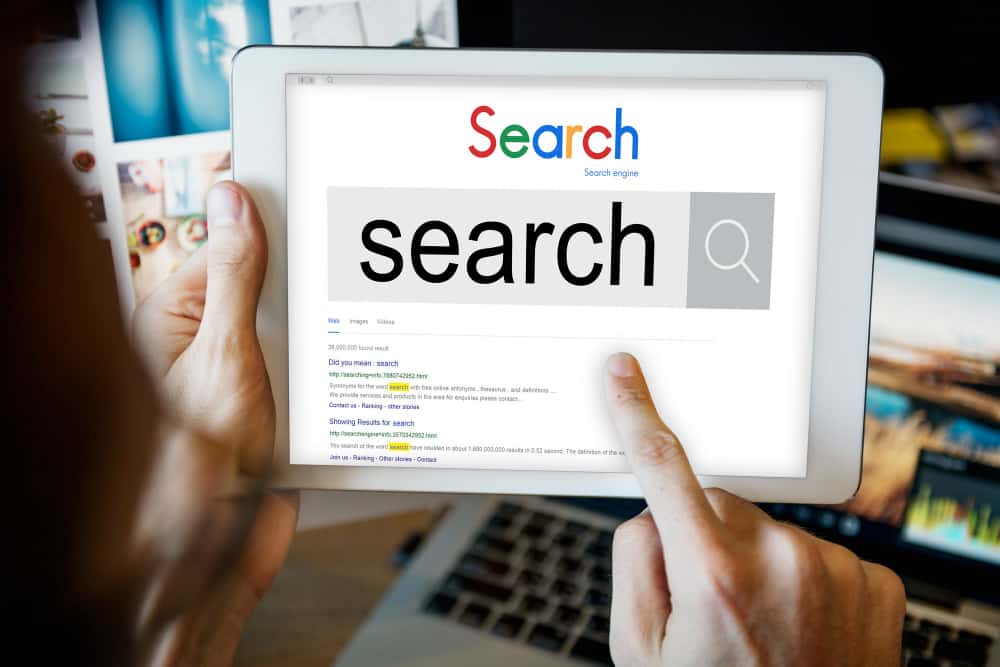 mains d'un homme qui tiennent une tablette blanche avec "Search" écrit dessus, site web professionnel