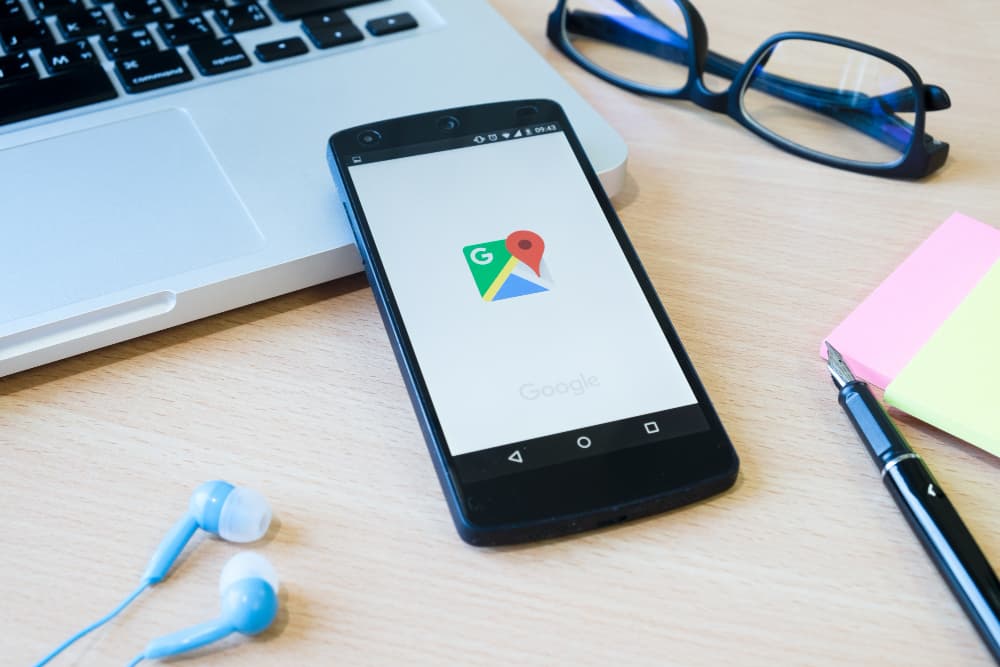 un smartphone posé sur un ordinateur portable, avec le logo google, barre de recherche google, google business profile
