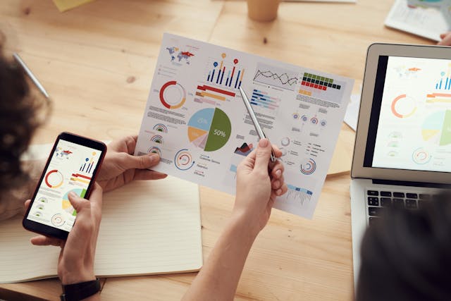 une main qui pointe avec un stylo sur une feuille, une autre ain qui tient la feuille, externaliser marketing digital