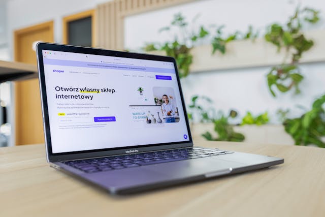 un ordinateur portable posé sur une able de bureau en bois, une fenêtre en arrière plan, landing page vs site vitrine