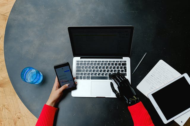 une main d'humain et une autre de robot qui tapent sur un clavier d'ordinateur, outils no-code IA entreprise