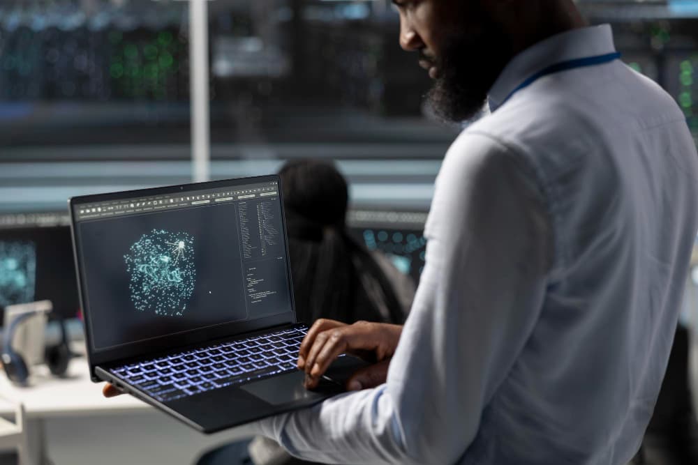 un homme e, chemise blanche vu de dos qui tient un ordinateur portable, agence no-code