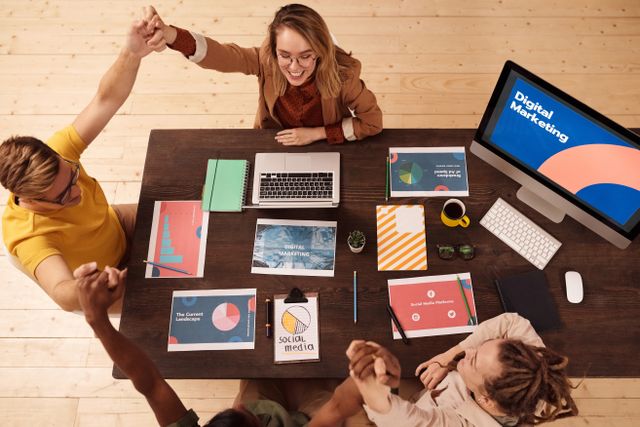 des collaborateurs dans une agence web marketing assis autour d'un bureau qui se tiennent la main